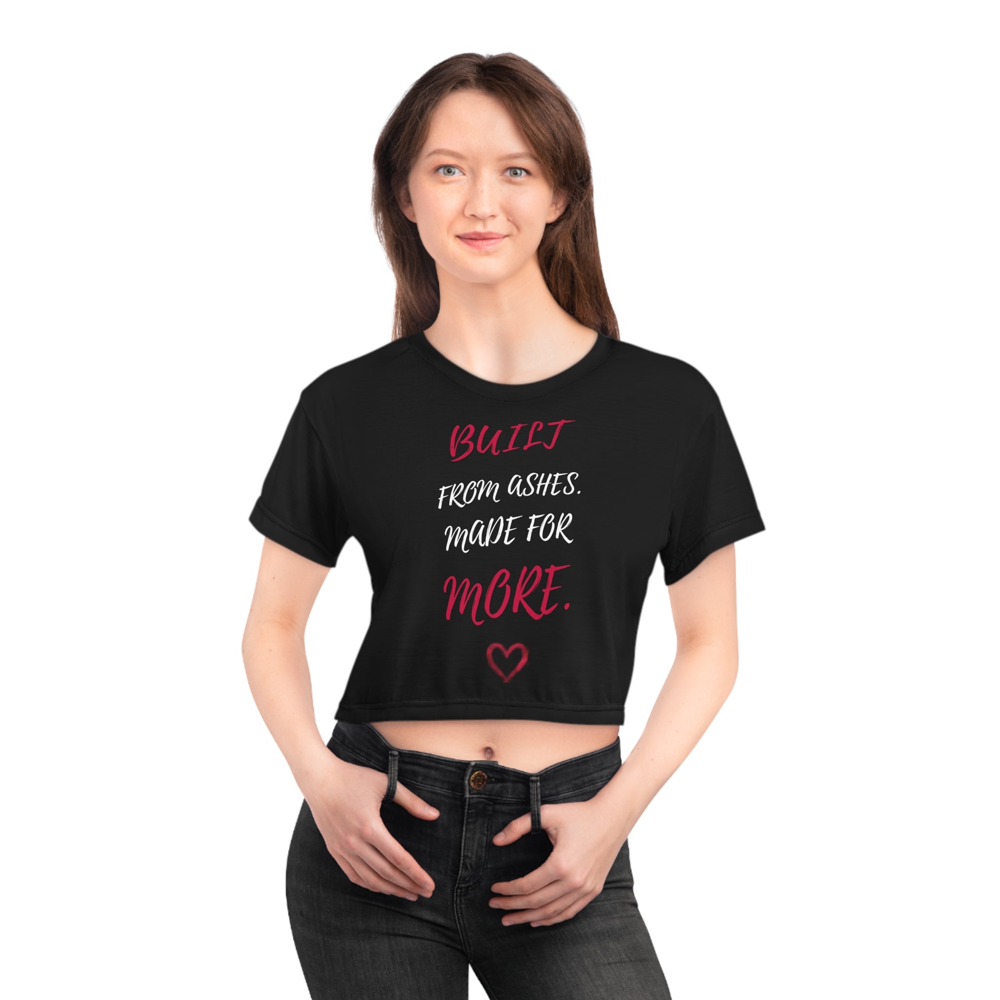 A woman is seen in the AliKat Rising Phoenix Wings Crop Tee — "Built from Ashes, Made for More" Inspirational Women's Top: a black, all-over print crop featuring bold white and red text and a small red heart beneath. This lightweight polyester tee is perfect for standing out as she smiles confidently with her hands in front.