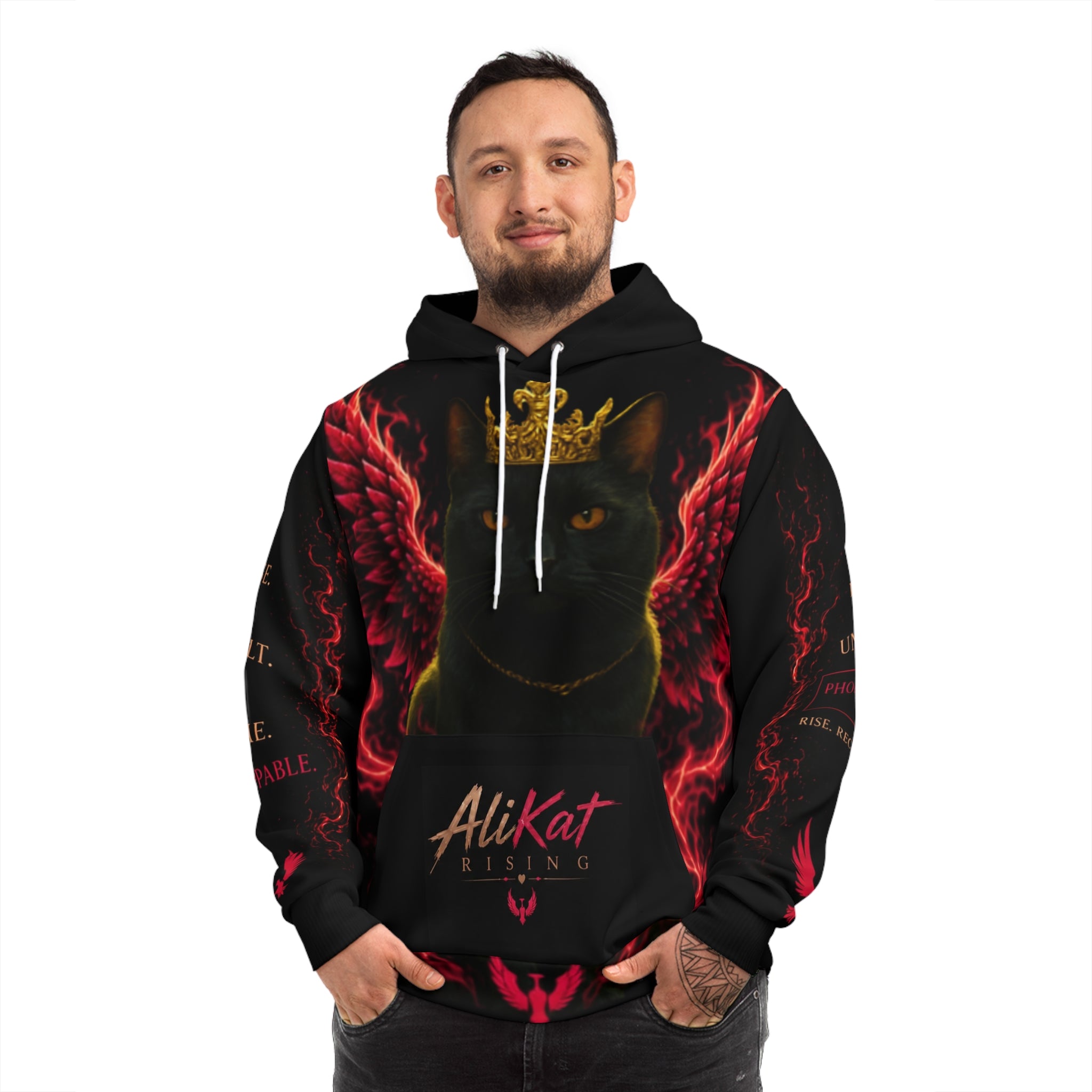 A man smiles and stands with his hands clasped in front of him, wearing the Phoenix Wings Hoodie — AliKat Flame Graphic Pullover by AliKat Rising. The black hoodie showcases a striking graphic of a black cat adorned with a gold crown and red wings, along with the signature AliKat Rising text. Available in sizes S, M, L, XL, and 2XL—with detailed length and width measurements for the perfect fit.
