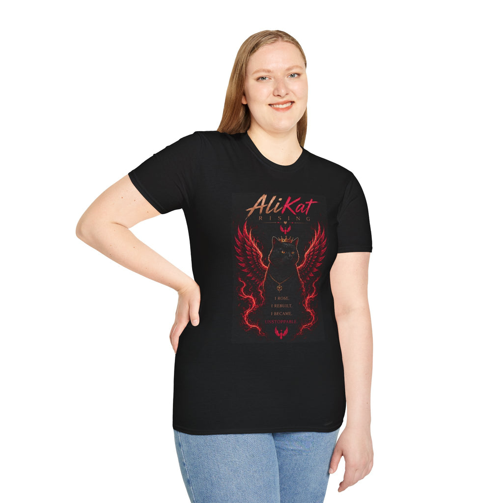 A woman smiles, wearing the AliKat Rising Phoenix Vol. 1 Graphic Tee featuring a bold red and black winged, crowned cat graphic with "AliKat" above. She stands with one hand on her hip against a white background. This unique AliKat Rising design is available in sizes S, M, L, XL, and 2XL.