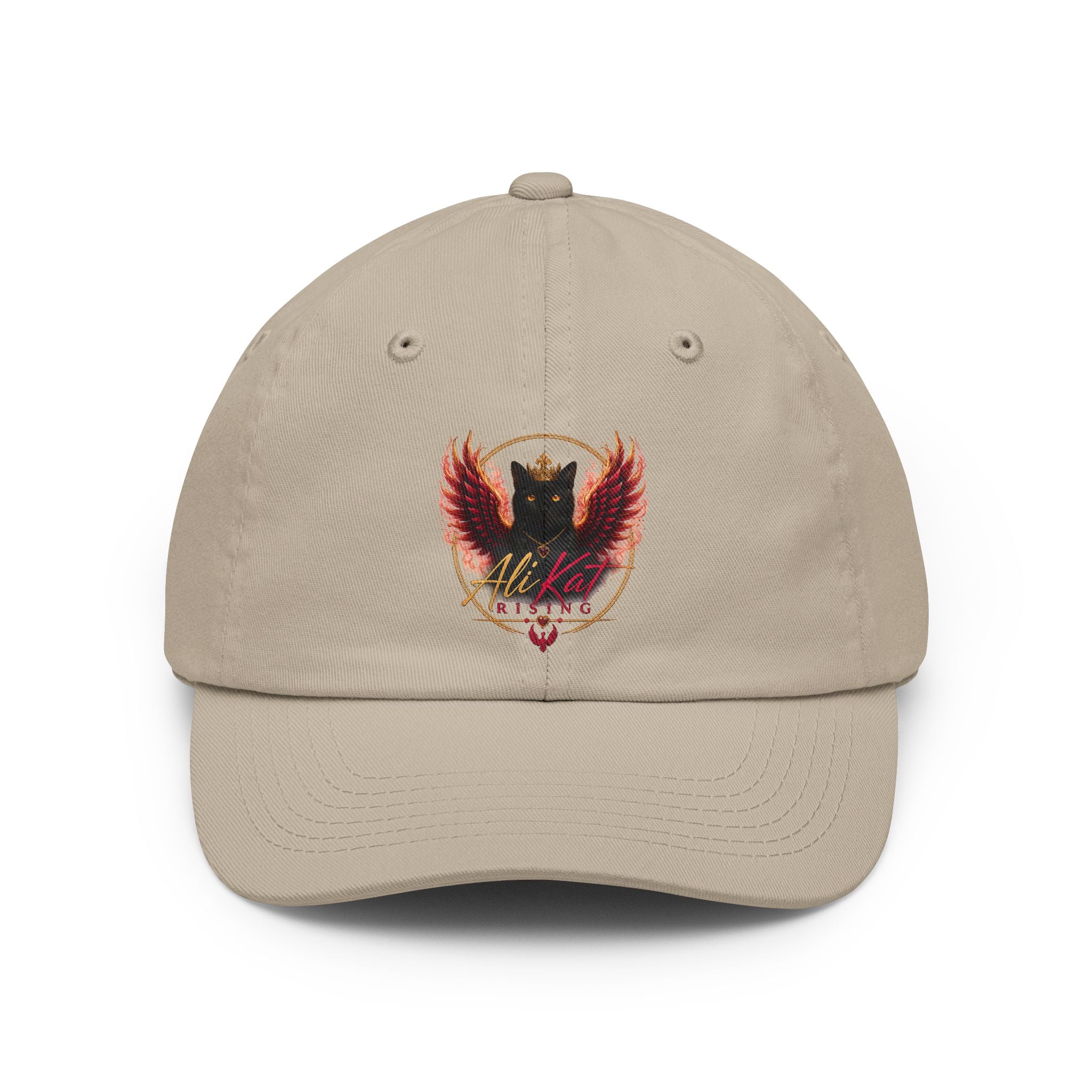 Introducing the AliKat Rising Phoenix vol 1 dad hat by AliKat Rising: a beige, low-profile cap adorned with an embroidered crest depicting a black cat with red wings and a crown, encircled by a golden ring. The stylized words "AliKat Rising" are stitched below the motif.